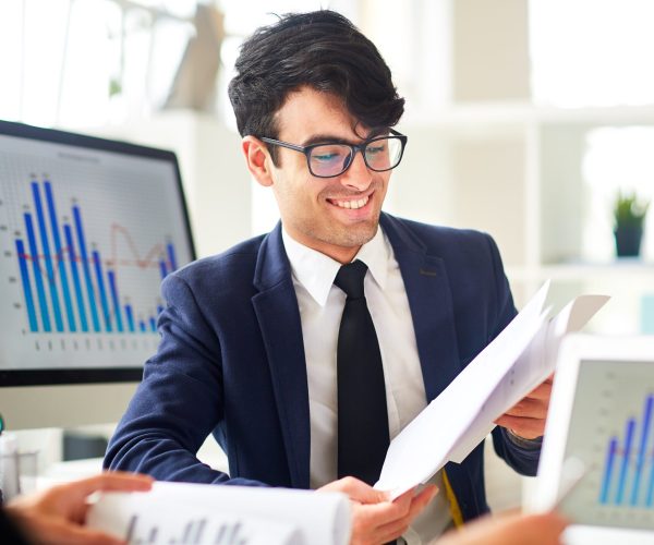 Young financier reading documents and discussing financial data with colleague